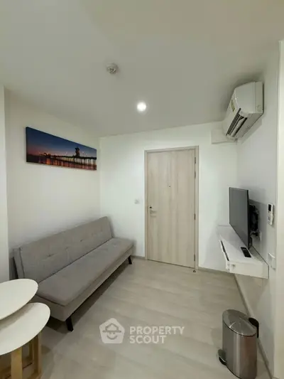 Modern living room with sleek furniture and wall-mounted TV in a cozy apartment.