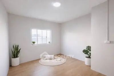 Minimalist room with wooden flooring, white walls, and potted plants, perfect for a serene living space.