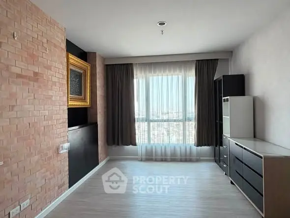 Spacious modern living room with large window and stylish brick accent wall.