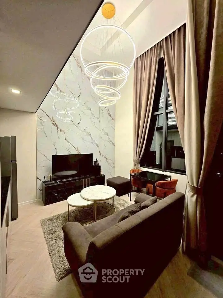 Luxurious modern living room with high ceilings, elegant lighting, and marble accent wall.