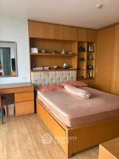Cozy bedroom with wooden furniture and built-in shelves, perfect for relaxation.