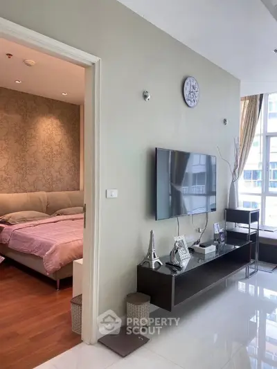 Modern living room with wall-mounted TV and view into cozy bedroom