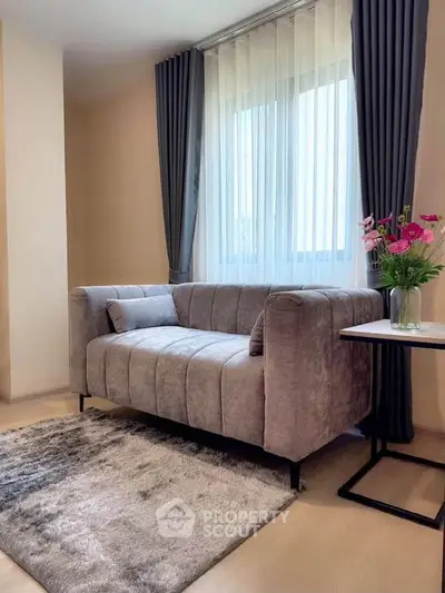 Cozy living room with plush gray sofa, elegant curtains, and a stylish side table with flowers.