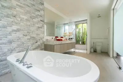 Luxurious modern bathroom with freestanding bathtub and elegant stone wall design.