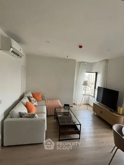 Modern living room with stylish decor and city view, featuring a cozy sectional sofa and large TV.