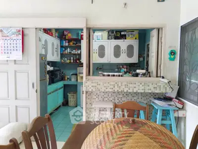 Charming vintage kitchen with open layout and cozy dining area, featuring retro cabinets and mosaic tile accents.