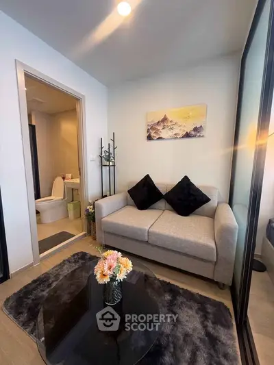 Cozy living room with modern decor and adjacent bathroom in a stylish apartment.