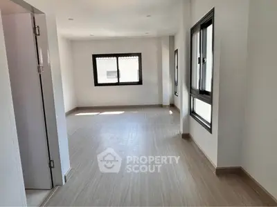 Spacious empty room with large windows and wooden flooring, perfect for customization.