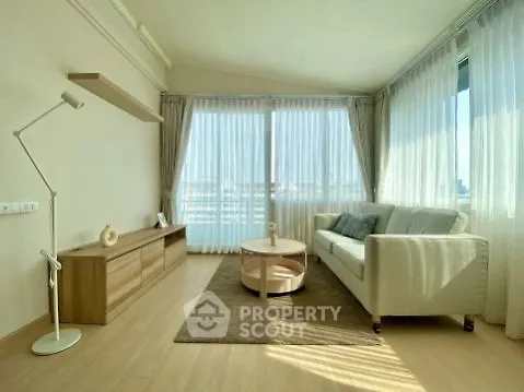 Bright and spacious living room with modern decor and large windows offering city views.