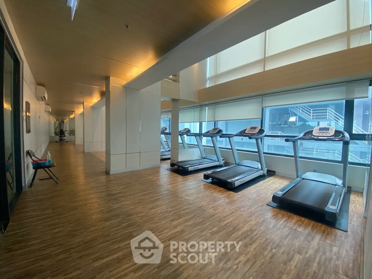 Modern gym with treadmills and wooden flooring in luxury apartment building