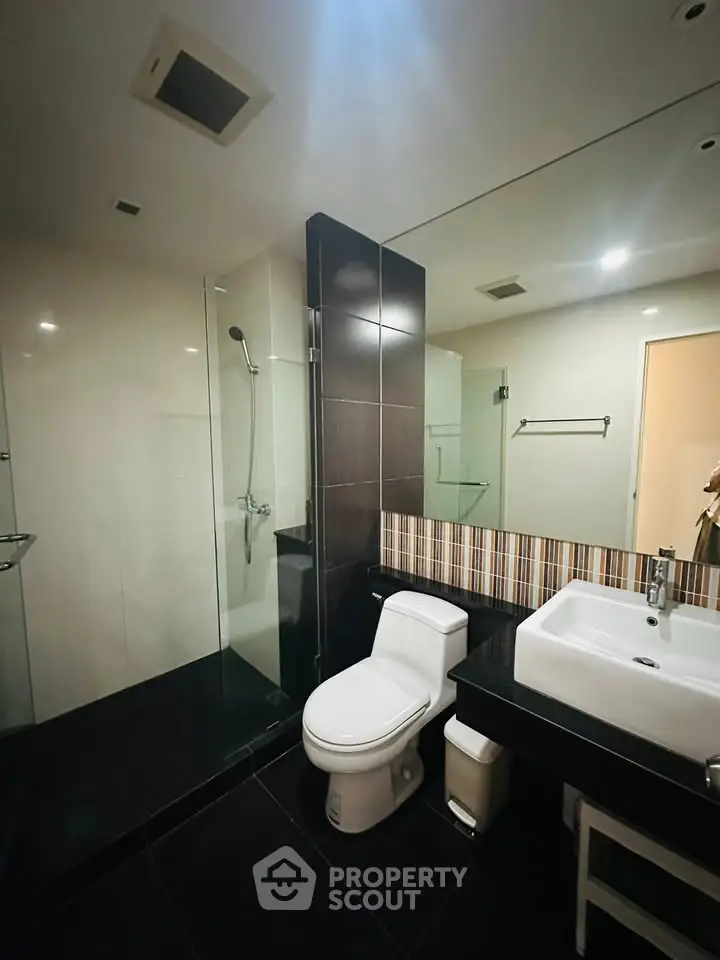 Modern bathroom with sleek design, featuring a glass shower and stylish fixtures.