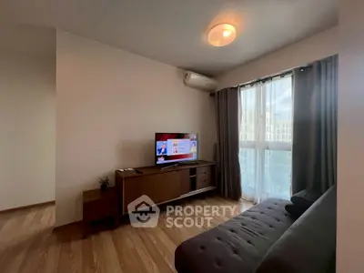 Cozy living room with modern sofa and TV, featuring natural light from large window.