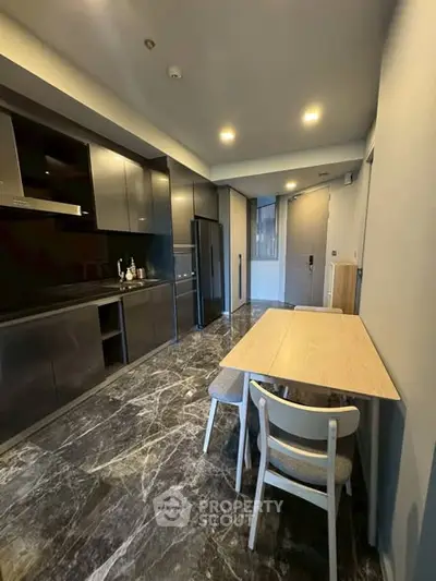 Modern kitchen with sleek cabinetry and dining area in contemporary apartment.