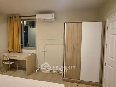 Cozy bedroom with modern wardrobe and desk, featuring air conditioning and natural lighting.