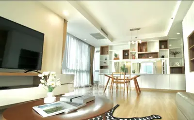 Modern living room with stylish decor and open dining area, featuring large windows and elegant furnishings.