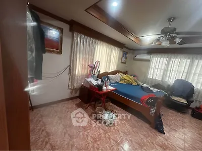 Spacious bedroom with wooden accents and natural light, featuring a ceiling fan and air conditioning.
