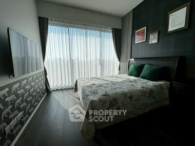 Modern bedroom with large window and stylish decor, featuring a wall-mounted TV and elegant bedding.