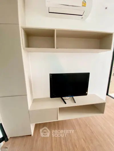 Modern living room with built-in shelving and air conditioning unit, featuring a sleek TV setup.
