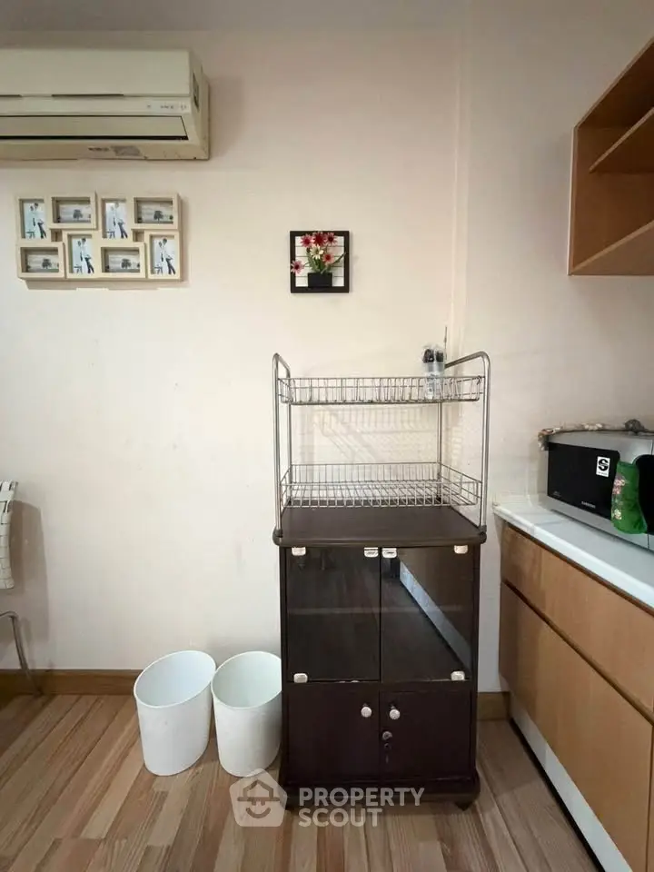 Cozy kitchen corner with wooden cabinets and air conditioning, perfect for compact living spaces.