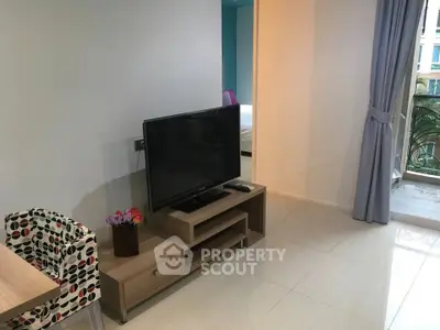Modern living room with sleek TV setup and balcony view in stylish apartment.