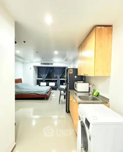 Modern studio apartment with open layout, featuring a compact kitchen and cozy sleeping area.