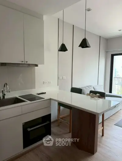 Modern kitchen with sleek design and open layout, featuring a cozy living area and balcony view.