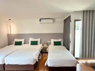 Spacious bedroom with three beds and modern decor, perfect for family or group stay.