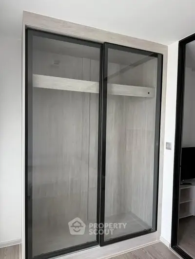 Modern built-in wardrobe with sliding glass doors in a stylish apartment interior.
