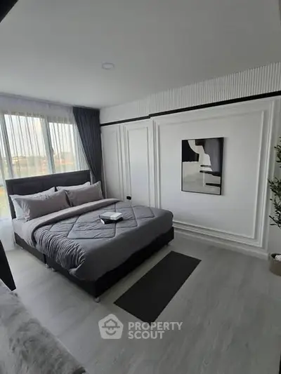 Modern bedroom with stylish decor and large window offering natural light