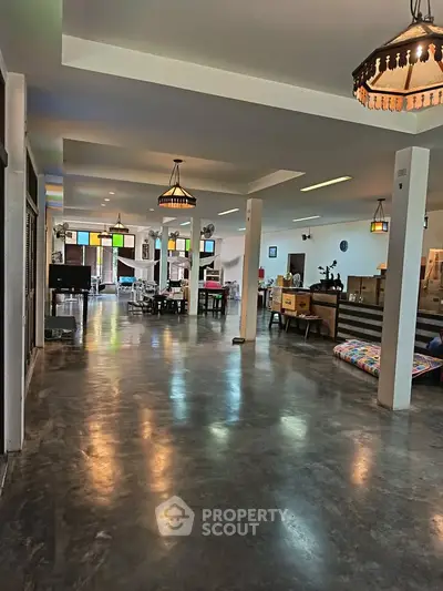 Spacious open-plan living area with modern decor and polished concrete floors, ideal for entertaining.