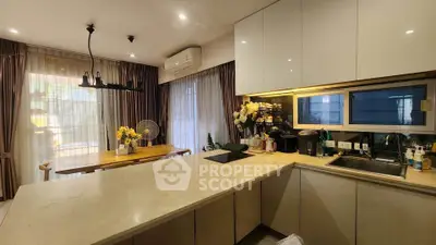 Modern kitchen with open layout and elegant dining area, featuring sleek cabinetry and ambient lighting.