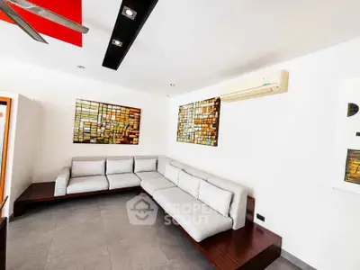 Modern living room with sleek sectional sofa and contemporary art on white walls.