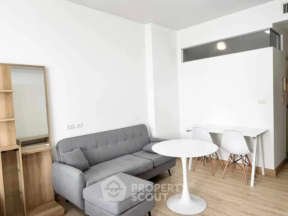 Modern living room with gray sofa, white table, and minimalist decor in a bright apartment.