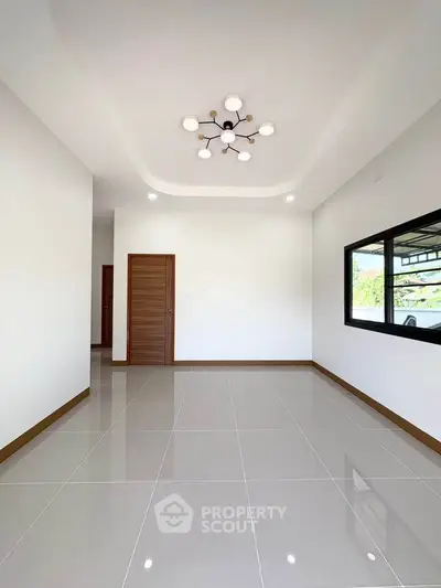 Spacious modern living room with elegant lighting and large window offering natural light.