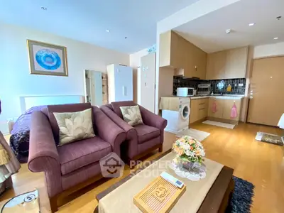 Cozy open-plan living room with kitchen, featuring plush sofas and modern appliances.