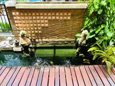 Charming garden pond with decorative statues and lush greenery, perfect for serene outdoor living.
