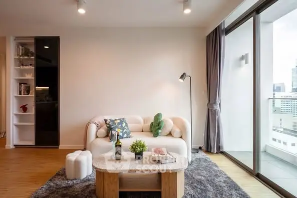 Stylish living room with cozy seating and balcony view in modern apartment.