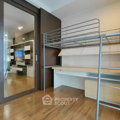 Modern bedroom with loft bed and built-in desk, featuring sleek wooden flooring and glass partition.