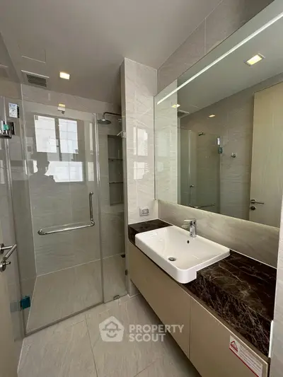 Modern bathroom with glass shower and sleek vanity in luxury apartment.