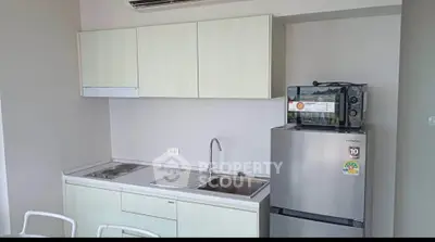 Modern compact kitchen with sleek cabinetry and stainless steel appliances in a cozy apartment.