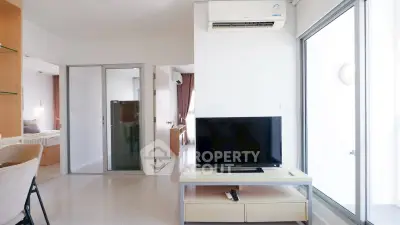 Modern living room with TV, air conditioning, and sliding glass doors leading to a bedroom.