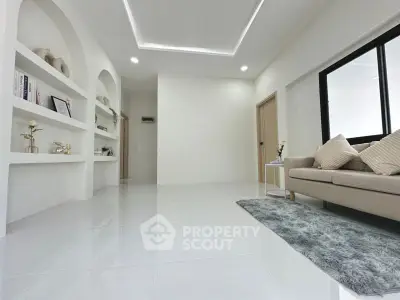 Modern minimalist living room with sleek white flooring and cozy beige sofa.