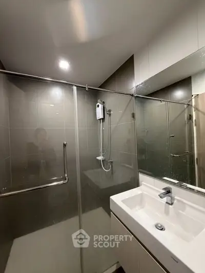 Modern bathroom with glass shower enclosure and sleek vanity in contemporary apartment.