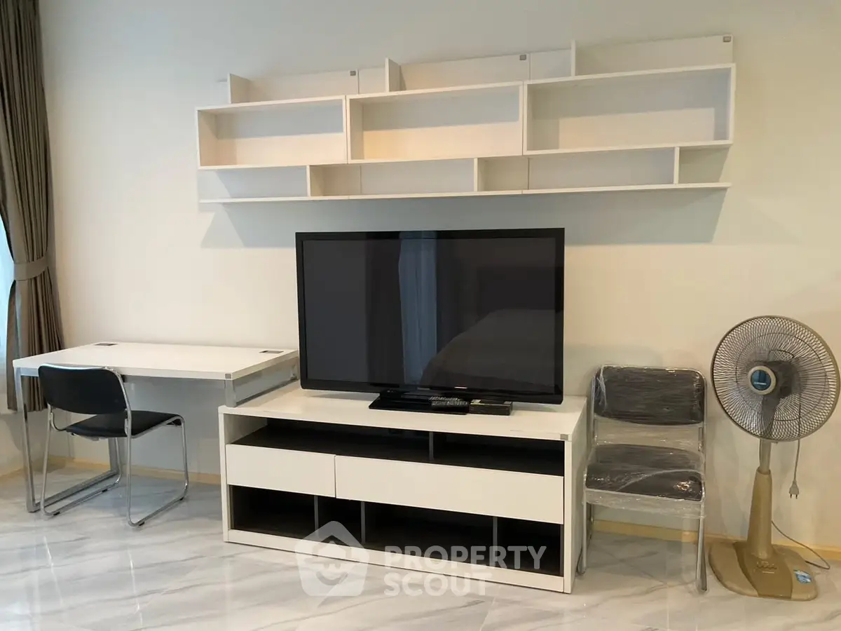 Modern living room with sleek TV stand, wall shelves, and stylish desk setup.