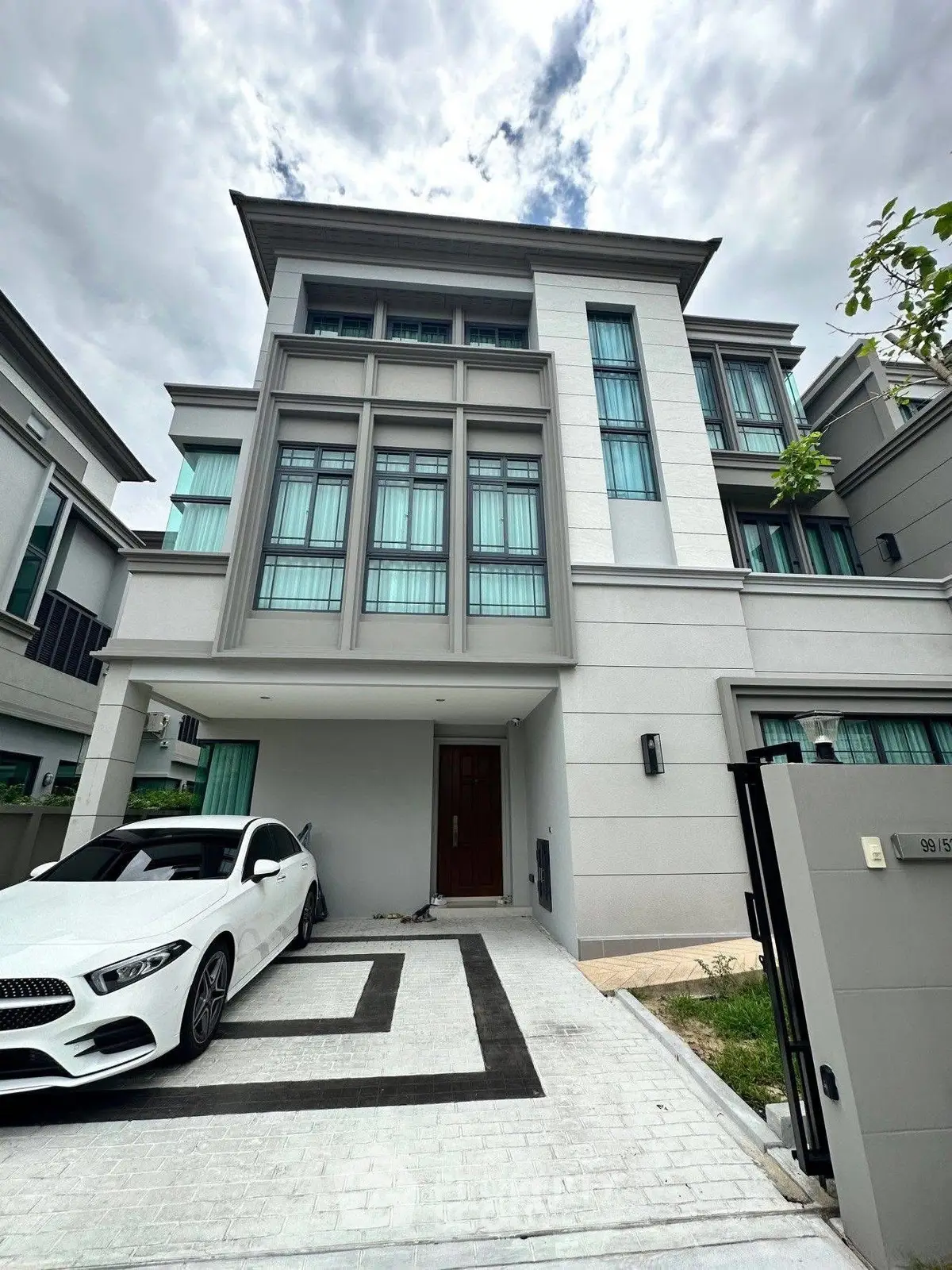 Modern three-story townhouse with sleek design and luxury car parked in driveway.