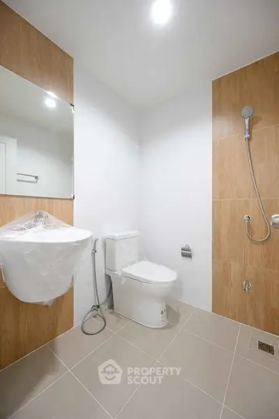 Modern bathroom with sleek fixtures and wood panel accents, featuring a shower and toilet.