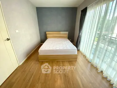 Spacious bedroom with wooden flooring and large window for natural light