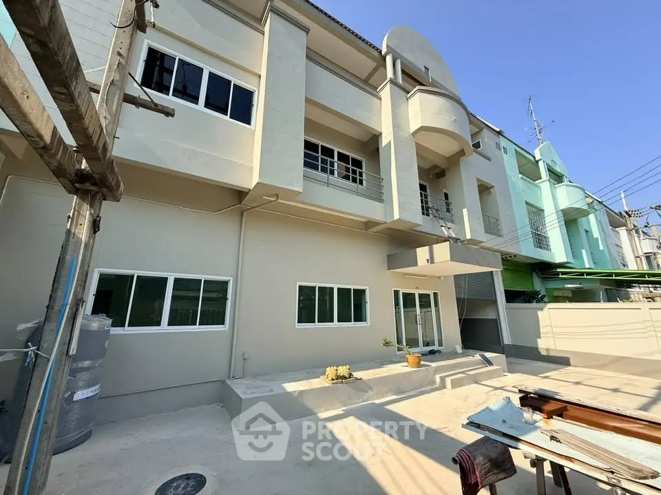 Modern townhouse exterior with clean lines and large windows under a clear blue sky.