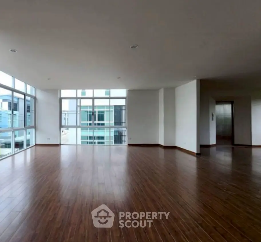 Spacious modern living room with large windows and wooden flooring