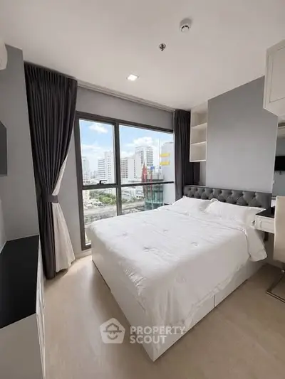 Modern bedroom with city view, featuring a large window and elegant decor.